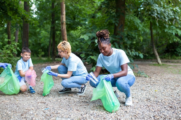 Un grupo de personas limpian juntas en un parque público protegiendo el medio ambiente Una mujer en primer plano con una bolsa de basura en la mano limpia el parque