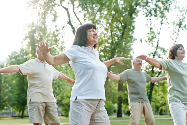 Grupo de personas maduras haciendo yoga juntos durante las clases al aire libre