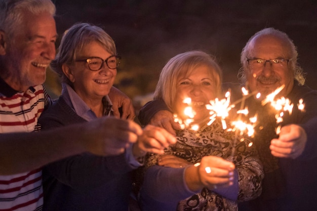 Grupo de personas mayores celebran juntos en amistad con fuego de bengala por la noche Víspera de año nuevo y evento de fiesta concepto de vida nocturna estilo de vida con hombres y mujeres maduros divirtiéndose