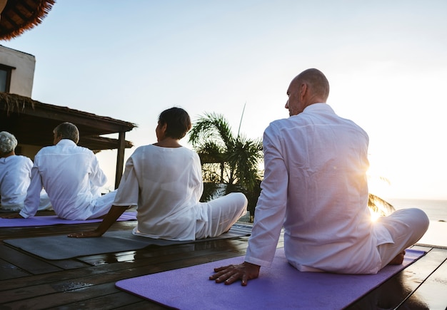 Grupo de personas mayores practicando yoga en la piscina