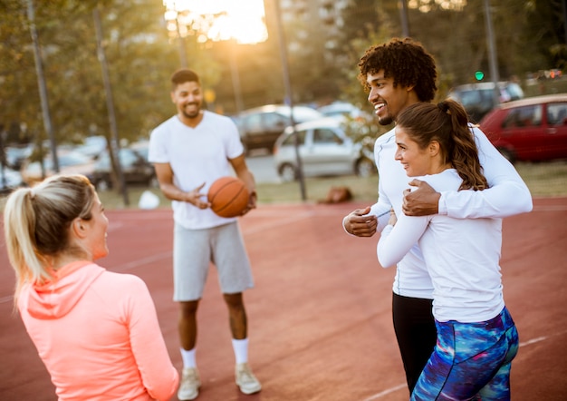 Grupo de personas multiétnicas jugando baloncesto en la cancha