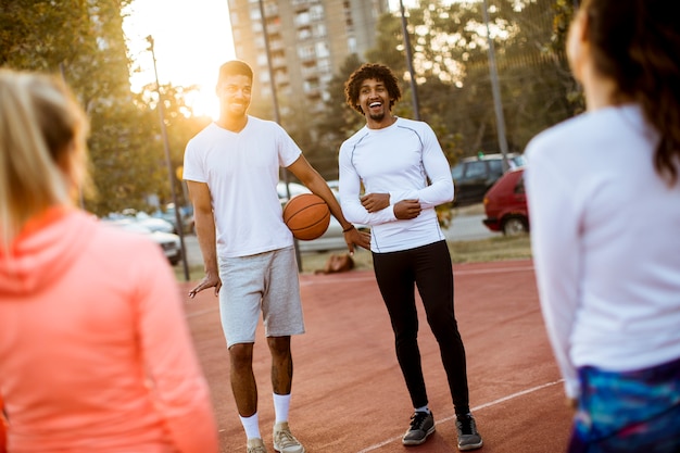 Grupo de personas multiétnicas jugando baloncesto en la cancha