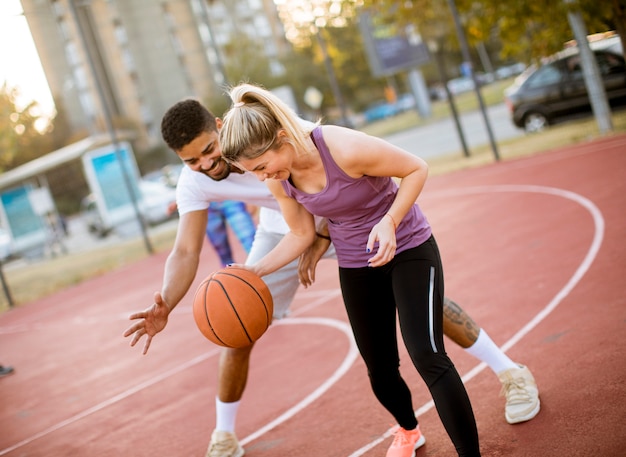 Grupo de personas multiétnicas jugando baloncesto en la cancha