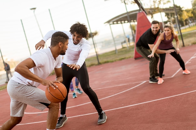 Grupo de personas multiétnicas jugando baloncesto en la cancha