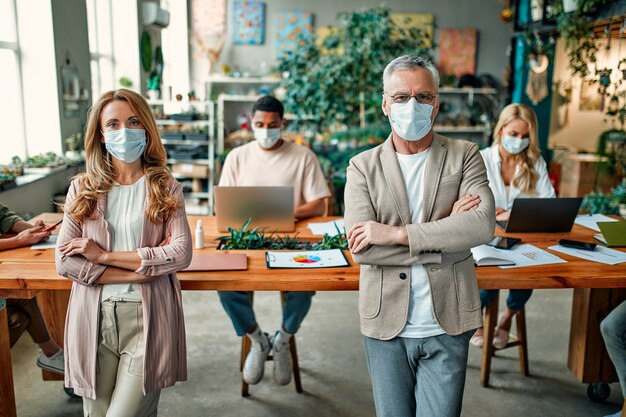 Grupo de personas multirraciales que trabajan en la oficina moderna durante el coronavirus. Los jóvenes empresarios y el jefe senior están trabajando juntos con máscaras protectoras faciales. Medidas preventivas durante Covid-19