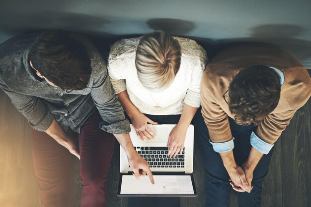 Un grupo de personas de negocios profesionales e investigadores de planificación que trabajan juntos en una computadora portátil mientras están sentados en la vista superior del piso Un equipo de diseñadores que buscan en la web o completan un proyecto