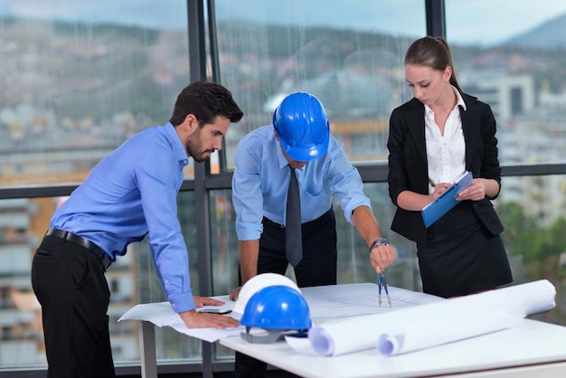 grupo de personas de negocios en reunión y presentación en una oficina moderna y luminosa con arquitecto ingeniero de construcción y trabajador que busca modelos de construcción y planes de planos