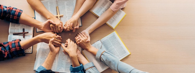 Foto grupo de personas orando juntas mientras se sostienen la mano vista de arriba floreciendo