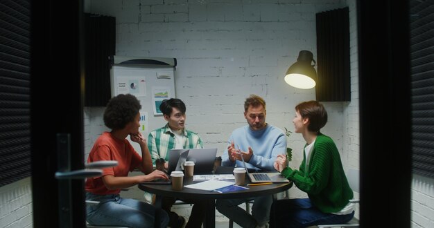 Un grupo de personas de pie cerca del lugar de trabajo de su colega y miran su portátil