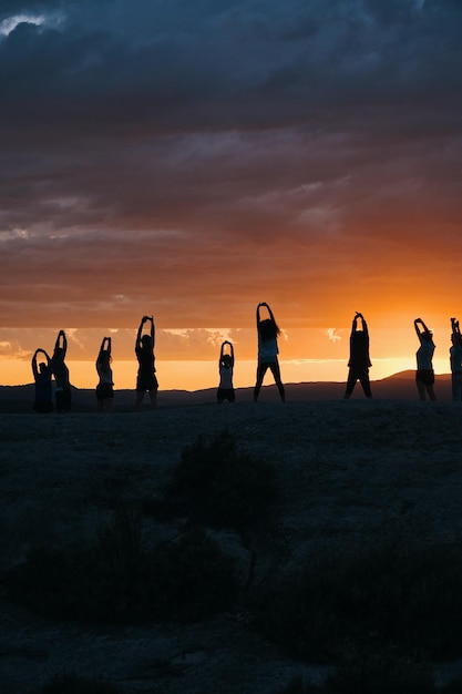 Un grupo de personas practicando yoga en el desierto al atardecer.