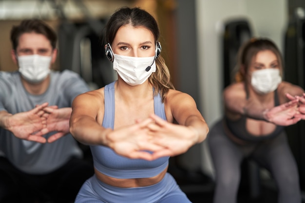 Grupo de personas que se ejercitan en un gimnasio con máscaras debido al covid-19