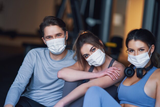 Grupo de personas que se ejercitan en un gimnasio con máscaras debido al covid-19