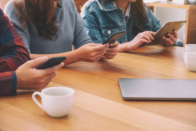 Grupo de personas que usan y miran el teléfono móvil y la tableta mientras están sentados juntos