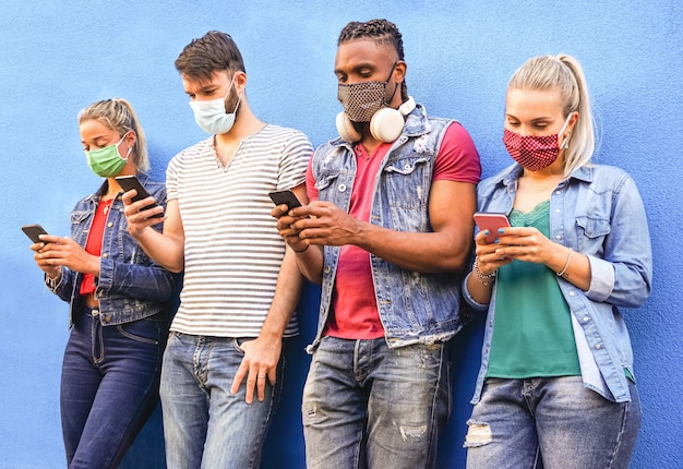 Grupo de personas que usan sus teléfonos inteligentes mientras usan máscaras faciales