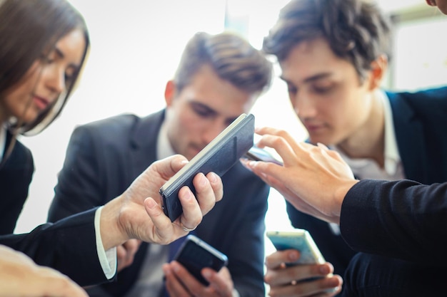 Grupo de personas que usan teléfonos inteligentes sentados en la reunión