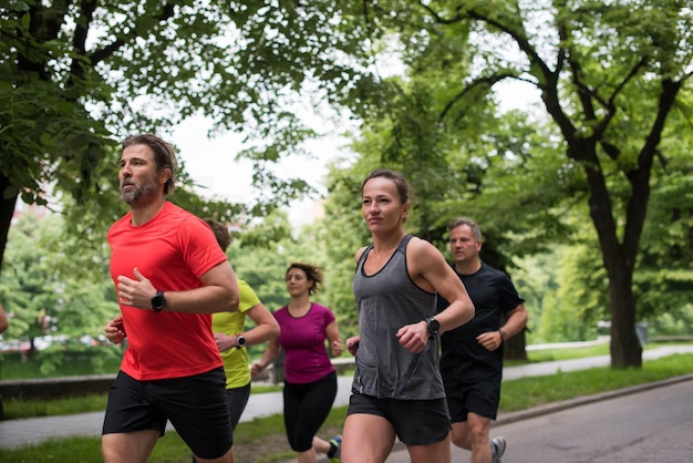 Foto grupo de personas sanas corriendo en el parque de la ciudad, equipo de corredores en el entrenamiento de la mañana