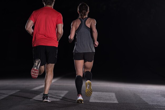 Grupo de personas sanas corriendo en el parque de la ciudad, equipo de corredores en entrenamiento nocturno