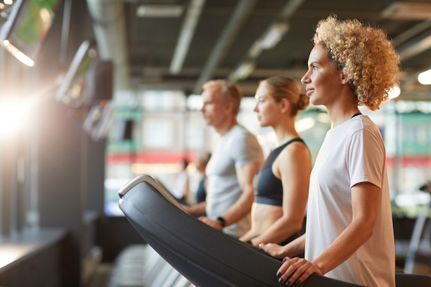 Grupo de personas sanas haciendo ejercicio en cintas de correr durante el entrenamiento deportivo en el club de salud