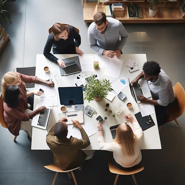 un grupo de personas sentadas alrededor de una mesa con computadoras portátiles y papeles en ella