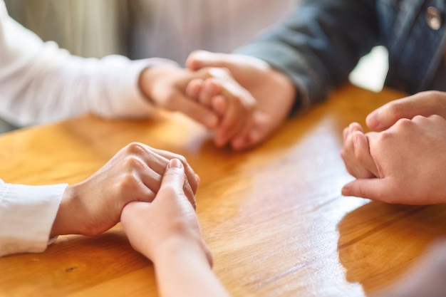 Grupo de personas sentadas en un círculo tomados de la mano y rezar juntos o en sesión de terapia