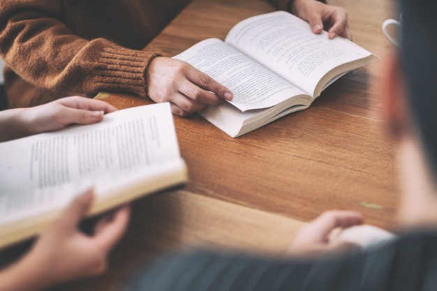 Grupo de personas sentadas y disfrutaron leyendo libros juntos sobre la mesa de madera