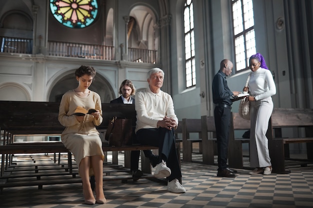 Grupo de personas sentadas en la iglesia y rezando para visitar la misa.