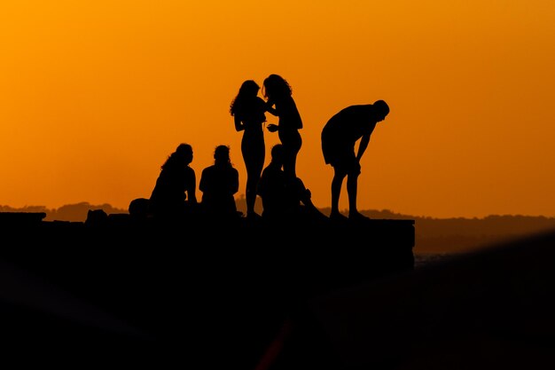 Grupo de personas en silueta se ven en el muelle de Porto da Barra contra la puesta de sol en la ciudad de Salvador Bahia