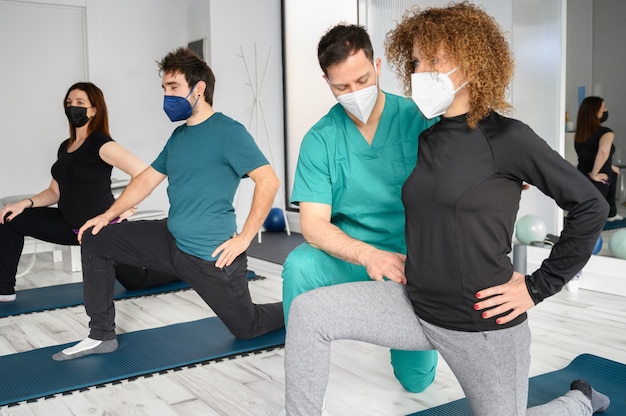 Grupo de personas sobre colchonetas de yoga asistidas por fisioterapeuta en la clínica de rehabilitación.