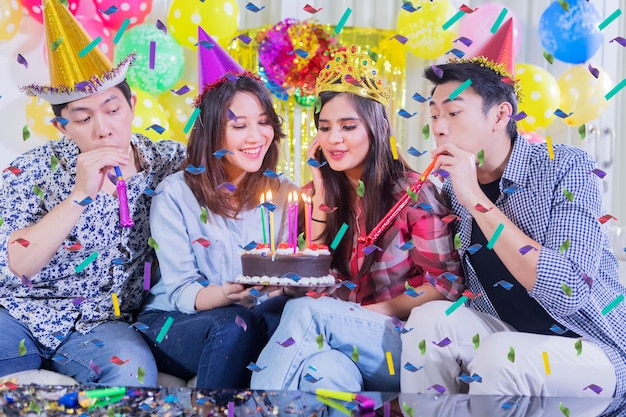 Grupo de personas soplan velas en el pastel de cumpleaños