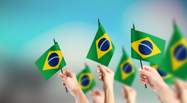 Un grupo de personas sostiene pequeñas banderas de Brasil en sus manos
