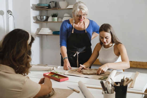 Grupo de personas en el taller de cerámica en un acogedor estudio trabajando con arcilla