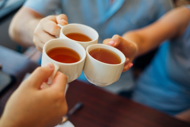 Grupo de personas tintineando tazas con té