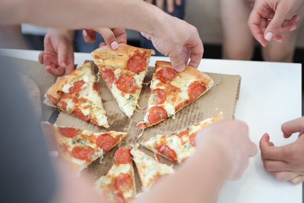 Grupo de personas tomando porciones de pizza closeup