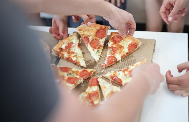 Foto grupo de personas tomando rebanadas de pizza en primer plano