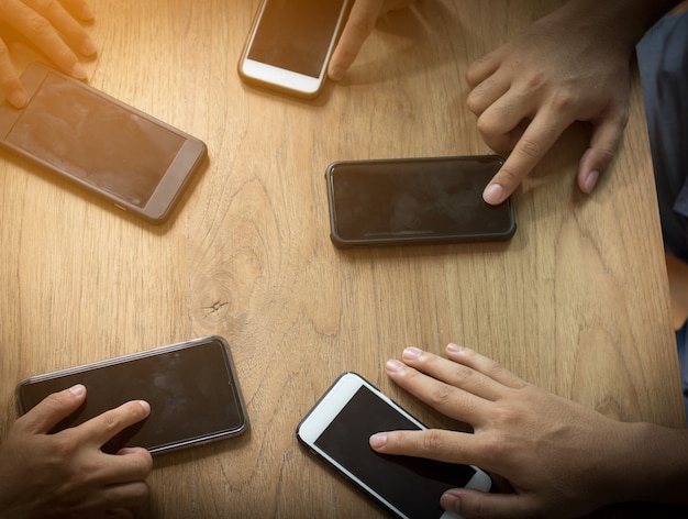 grupo de personas utiliza el teléfono en la mesa de madera para conectarse y comunicarse