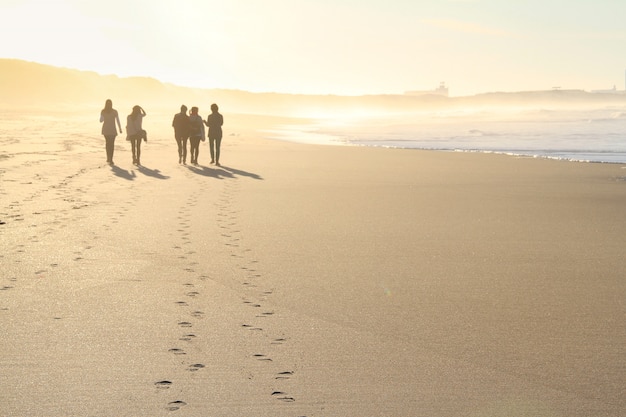 Grupo pessoas, andar praia, em, pôr do sol