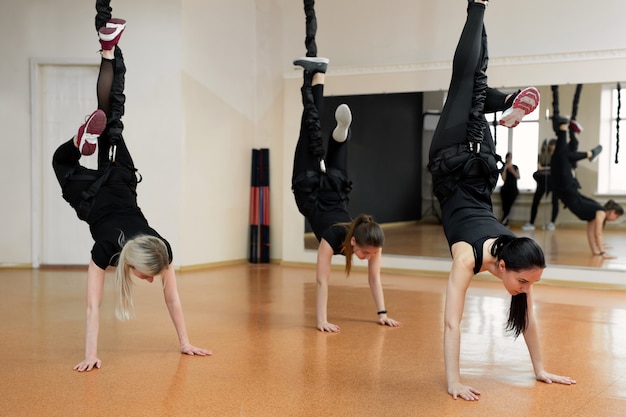 Grupo de primer plano de niñas colgando de gomas elásticas en el gimnasio.