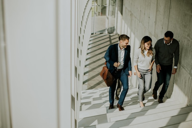 Grupo de profesionales de negocios corporativos subiendo escaleras en el pasillo de la oficina