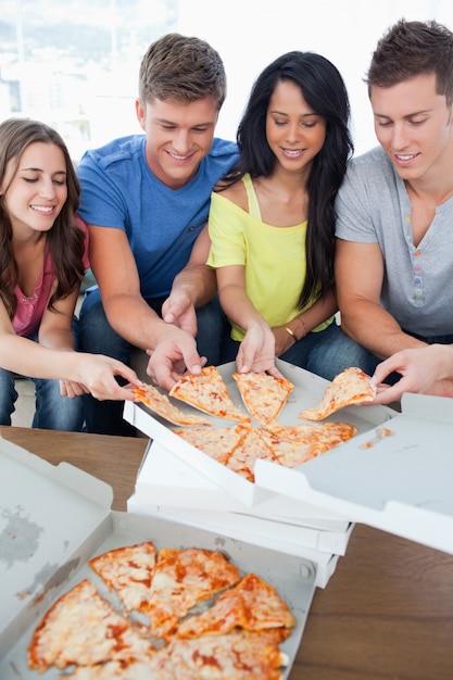 Un grupo que se agarra una porción de la pizza