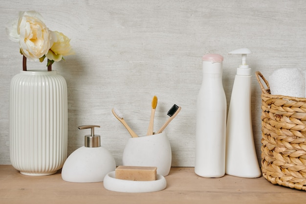 Foto un grupo de recipientes blancos con cosas para el cuidado del cuerpo, una canasta con toallas limpias y un jarrón con flores.