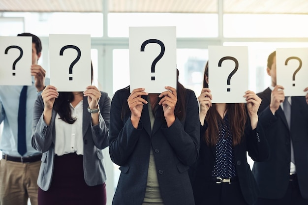 Grupo de signos de pregunta y papel en el negocio de la oficina y colegas con signos desconocidos o profesionales Preguntando misterio y personas corporativas con cobertura trabajo en equipo e incierto en el trabajo y confusión