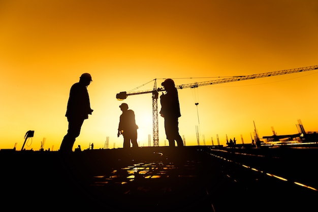 grupo de silueta de trabajador e ingeniero civil en uniforme de seguridad instalan acero reforzado