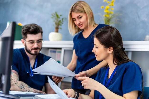 Grupo sonriente de médicos diversos leyendo juntos las notas de un paciente mientras están en el consultorio del hospital