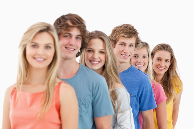 Un grupo de sonrientes parados uno detrás del otro en un ángulo.