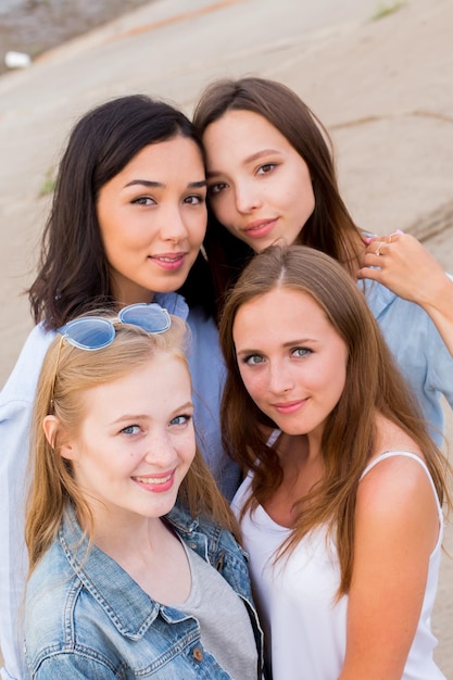 Grupo sorridente de estudantes do sexo feminino em roupas de verão posando juntos ao ar livre e olhando para a câmera, tire uma selfie