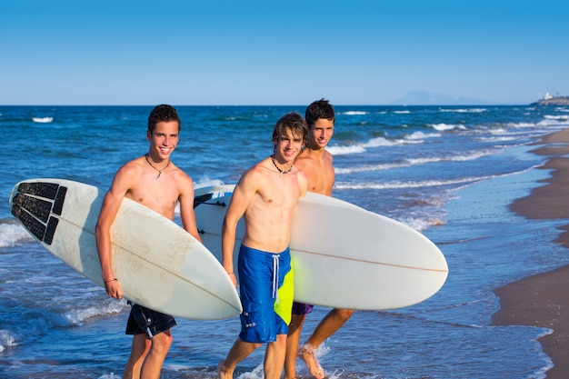 Grupo de surfistas varones saliendo de la playa.