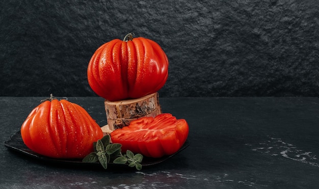 Un grupo de tomates grandes Costoluto con orégano en un espacio de fondo gris para texto