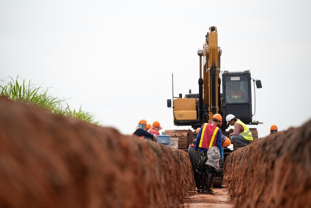 Grupo de trabajador y el ingeniero de la construcción usan drenaje uniforme de agua de excavación de seguridad