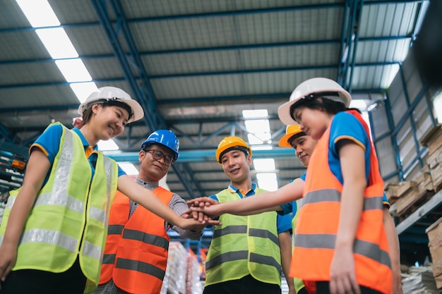 Grupo de trabajadores asiáticos de almacenes industriales en la pila de mano de la suite de seguridad celebran el compromiso exitoso o de trato Cadena de suministro de logística y negocio de almacén Unidad de trabajo en equipo bajo el concepto de vista