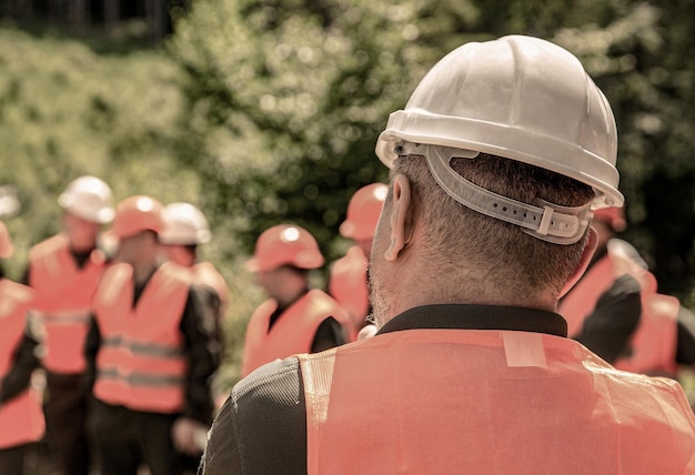 Grupo de trabajadores con chaleco de seguridad Concepto de construcción Arquitecto ingenieros en el sitio de construcción Hombre constructor Casco constructor Muchos trabajadores de la construcción casco